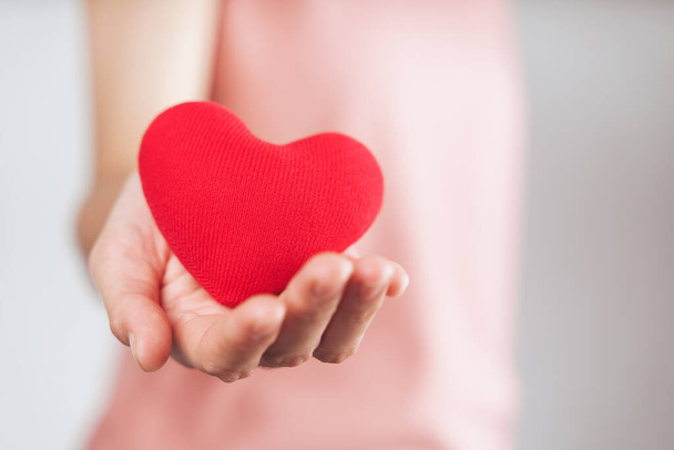 Женщина держит красное сердце, любовь, медицинское страхование, пожертвование, счастливый благотворительный волонтер, Всемирный день психического здоровья, Всемирный день сердца, День Святого Валентина - Фото, изображение