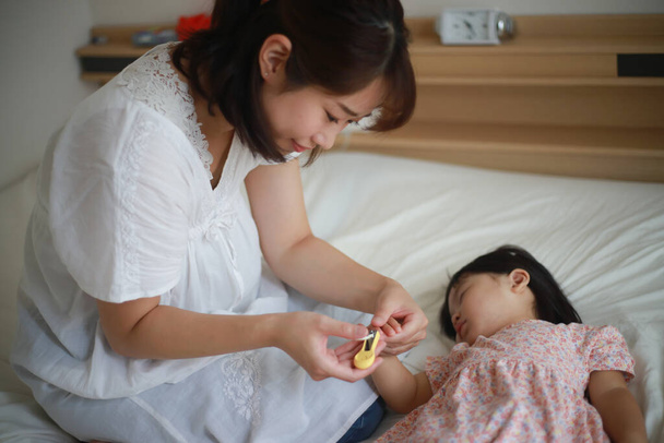 Matka cięcia paznokcie śpiącej dziewczyny - Zdjęcie, obraz