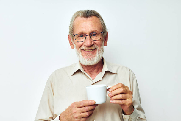 an elderly man holding a mug on a white background and smiling - Photo, Image
