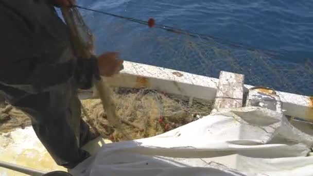 Halászhálók gyülekeznek a hajón.Egy halász hálókat gyűjt össze.Nylon háló lebegő zsinórral a műanyag úszókhoz.Halászhálók gyűjtéseA hálók rácsszerű szerkezetben szőtt szálakból készült eszközök.. - Felvétel, videó