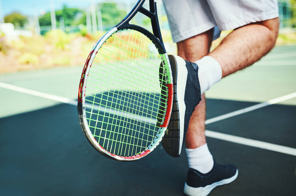 Hes always up for a challenge. Cropped shot of an unrecognizable male tennis player kicking his tennis racket outdoors on a tennis court. - 写真・画像