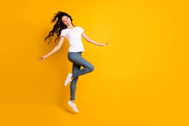 Full length body size view of lovely cheerful girl jumping having fun dancing isolated over bright yellow color background - Foto, afbeelding