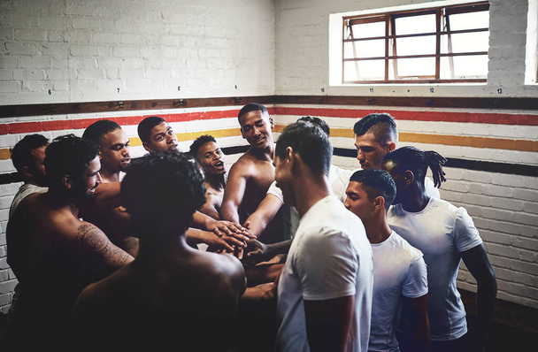 Reuniéndose con el espíritu de ganar. Recorte de un grupo de jóvenes jugadores de rugby guapos de pie juntos en un grupo en un vestuario. - Foto, imagen