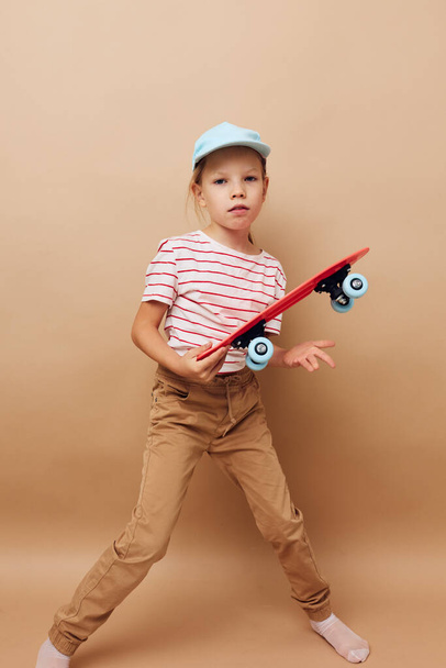 cute girl skateboard in hand posing baby clothes fun isolated background - Foto, Imagem