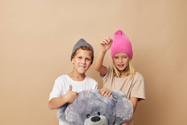 Portrait of cute children in hats with a teddy bear friendship isolated background - Zdjęcie, obraz