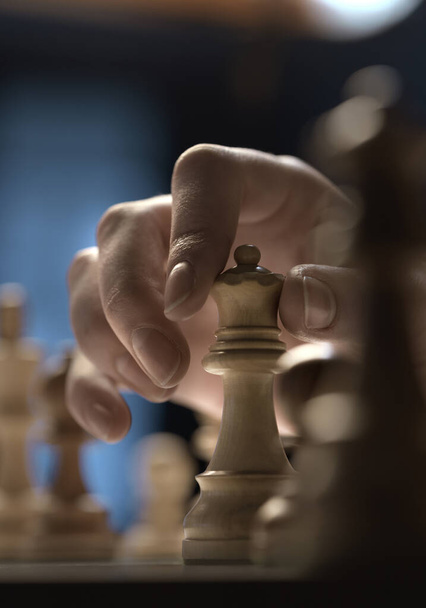 Man playing chess and moving a piece on the chessboard, hand close up, strategy games concept - Фото, зображення