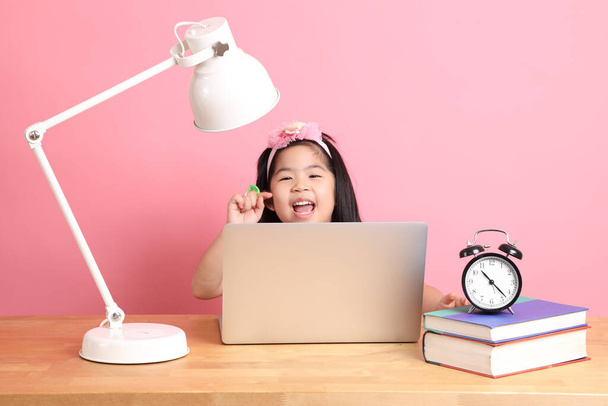 Söpö aasialainen tyttö oppimisen Internetistä kannettavan kanssa vaaleanpunainen tausta. - Valokuva, kuva