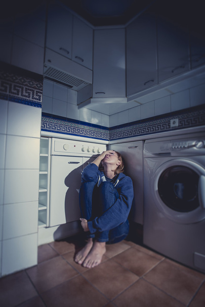 einsame und kranke Frau sitzt in Stressdepression und Traurigkeit auf dem Küchenboden - Foto, Bild