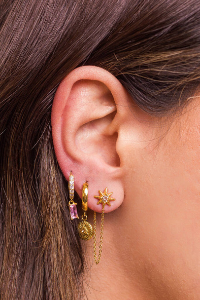 Női fül többszörös piercingekkel gyönyörű fülbevalót visel cirkóniummal - részletek rögzítése. Gyönyörű Valentin-napi ajándék.. - Fotó, kép