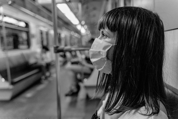 Epidemic. A woman in a protective mask rides in a subway car. - Foto, imagen