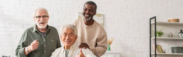 Sorridente uomo asiatico mostrando come gesto vicino amici multietnici a casa, banner  - Foto, immagini