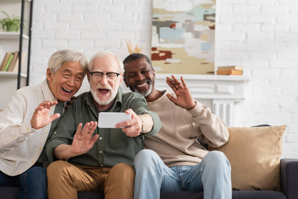 Elderly multiethnic friends having video call on cellphone at home  - Foto, Imagen