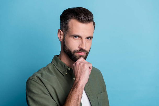 Photo of confident intelligent handsome guy finger chin think wear green shirt isolated blue color background - Foto, afbeelding