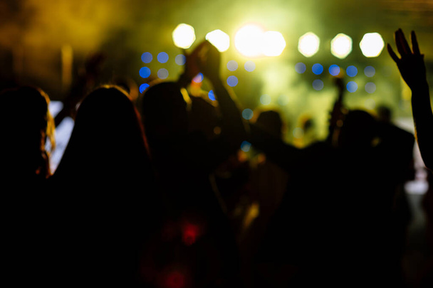 веселий натовп перед яскраво-жовтим сценічним вогнем. Силуетне зображення людей, які танцюють у нічному клубі диско або концерті на музичному фестивалі
 - Фото, зображення