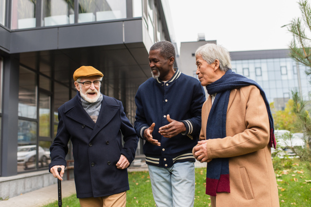 Interracial senior people talking while walking on urban street  - Фото, зображення
