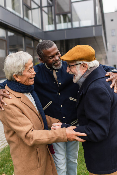 Usmívající se multietničtí muži objímající se na městské ulici  - Fotografie, Obrázek