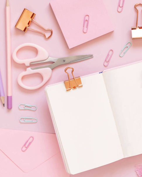 Opened notebook and Pink school accessories on pastel pink, Top view, textbook mockup. Girly workplace with scissors, pencils, paperclips, sticky note paper and envelope. Back to school concept - Photo, Image