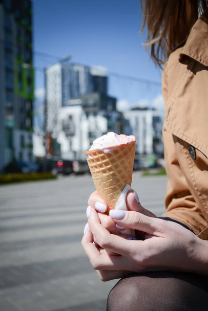 Ice cream in a wafer cup in a woman's hands in the city - 写真・画像
