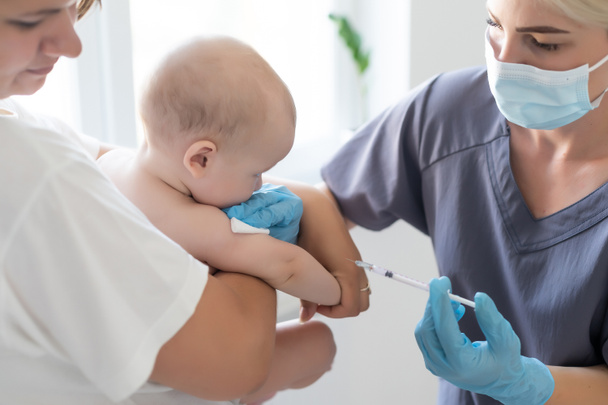 医者は白い背景で赤ちゃんの予防接種を行います. - 写真・画像