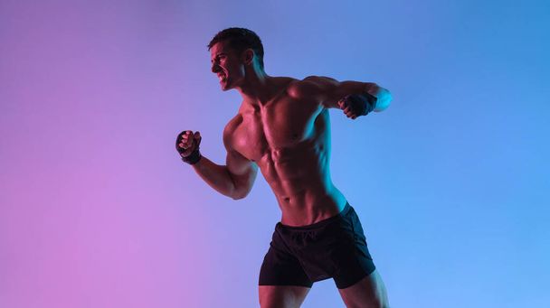 Boxing concept. Sportsman muay thai boxer fighting in gloves. Isolated on neon background. Copy Space. - Foto, afbeelding
