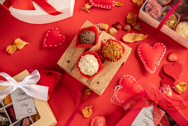 шоколадные конфеты, подарочная коробка и красная лента на красном фоне. - Фото, изображение