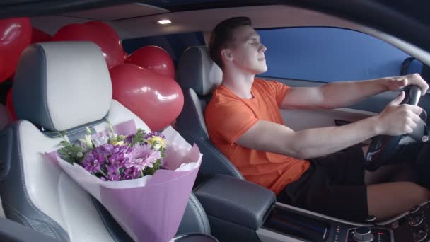 Ένας ευτυχισμένος τύπος μπαίνει σε ένα αυτοκίνητο με ένα μπουκέτο λουλούδια. Δώρα - Πλάνα, βίντεο