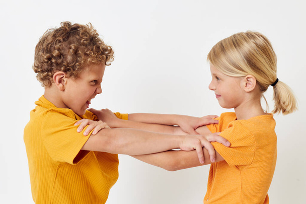 Cute stylish kids in yellow t-shirts standing side by side childhood emotions light background unaltered - Foto, Imagen