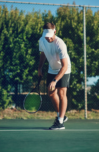 Have fun and enjoy the game. Shot of a sporty young man playing tennis on a tennis court. - Valokuva, kuva