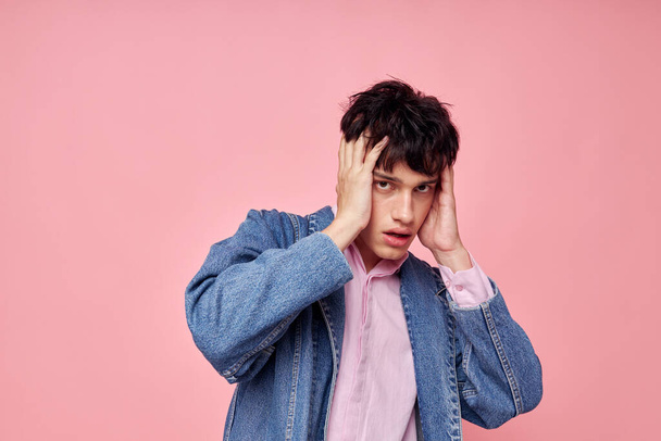 A young man fashion hairstyle posing clothing denim jacket modern style pink background unaltered - Foto, immagini