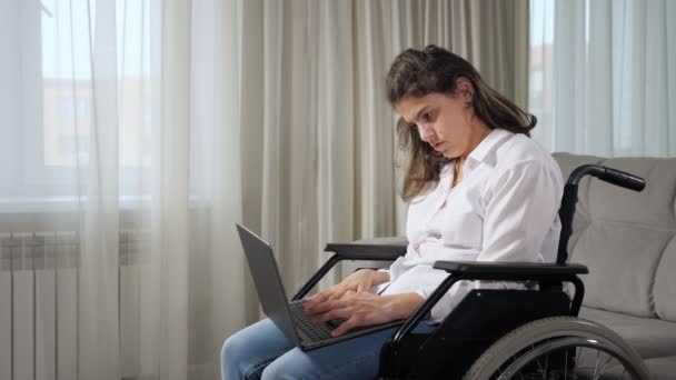 Γυναίκα με ειδικές ανάγκες εργάζεται online σε φορητό υπολογιστή κάθεται σε αναπηρική καρέκλα - Πλάνα, βίντεο