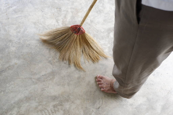 Woman using a broom to sweep the floor - Zdjęcie, obraz