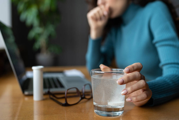 Closeup of painkiller dissolving in glass of water. Sick business woman take medical pill in office - Foto, afbeelding