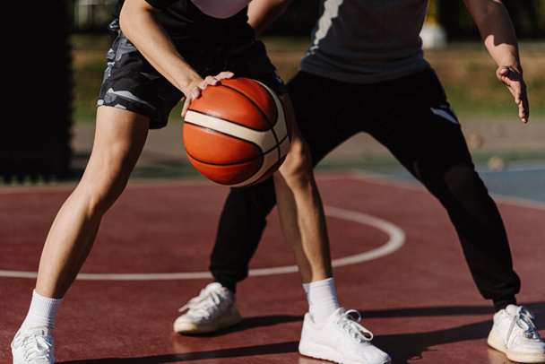 Concepto de deportes y recreación dos jugadores de baloncesto masculino disfrutando jugando baloncesto juntos en el campo de deportes. - Foto, imagen