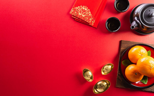 Decoraciones chinas de año nuevo hechas de paquetes rojos, lingotes de naranja y oro o bulto de oro sobre un fondo rojo. caracteres chinos FU en el artículo se refieren a la fortuna buena suerte, riqueza, flujo de dinero. - Foto, imagen
