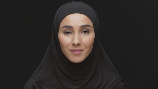 Primer plano retrato de estudio de una joven musulmana positiva de Oriente Medio usando el hijab tradicional sonriendo a la cámara - Imágenes, Vídeo