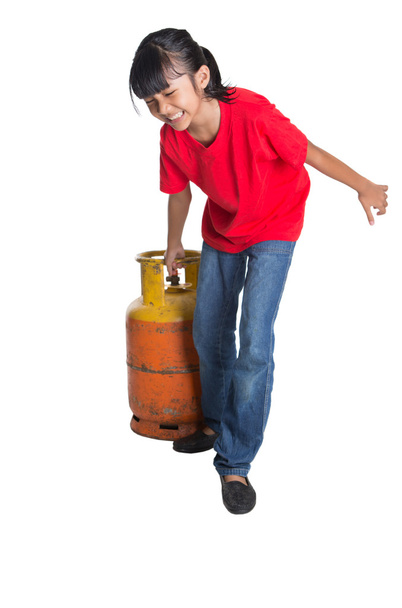 Joven chica asiática moviendo un viejo cilindro de gas propano sobre fondo blanco
 - Foto, imagen
