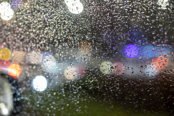 Yağmurda trafik sıkışıklığı sırasında arabanın ön camında bulanık bir arkaplan var. - Fotoğraf, Görsel