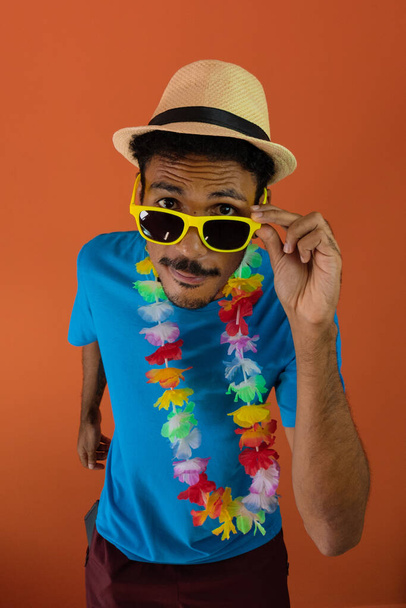 Μαύρος άντρας με κοστούμι για το καρναβάλι brazil απομονωμένος σε πορτοκαλί φόντο.  - Φωτογραφία, εικόνα