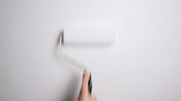 Ręka z Roller malowania ściany z białą farbą. Malowanie gołej ściany wałkiem lakierniczym z białą farbą. Rozdzielczość wideo 4K - Materiał filmowy, wideo