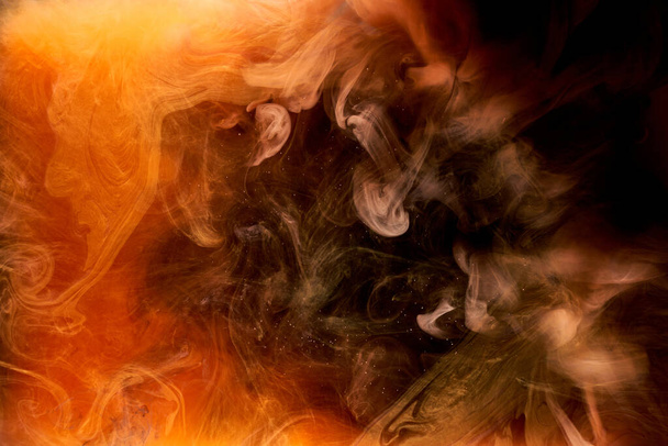Orange smoke on black ink background, colorful fog, abstract swirling ocean sea, acrylic paint pigment underwater - Foto, immagini