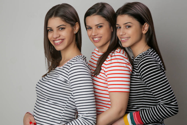 Drei glückliche schöne kaukasische Frauen in gestreiften T-Shirts, Studioaufnahme - Foto, Bild