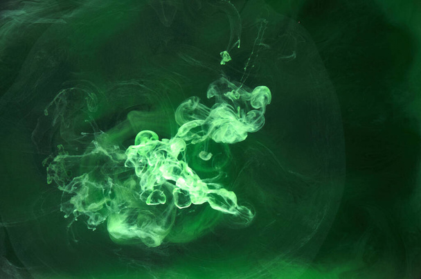 Green smoke on black ink background, colorful fog, abstract swirling emerald ocean sea, acrylic paint pigment underwater - Foto, Bild