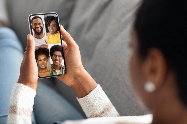 Female holding cellphone with happy black people faces on screen - Photo, Image