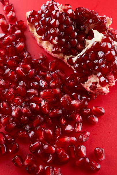 Ruby ripe fresh juicy sliced pomegranate isolated on red background - 写真・画像