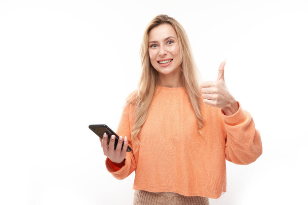 Beautiful blonde girl in casual showing blank phone screen thumbs up and smiling isolated on white studio background - Fotoğraf, Görsel