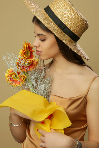 Studio plan de belle jeune femme en chapeau de paille tient bouquet de fleurs.  - Photo, image