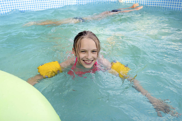The girl happily swims in the pool in the summer. - Fotoğraf, Görsel