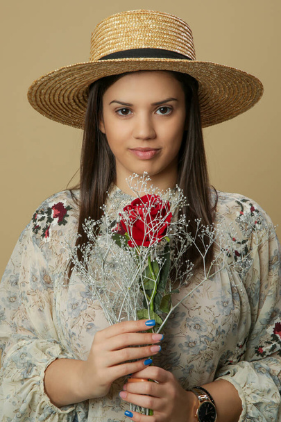 Studio záběr krásné mladé ženy v slamníku drží kytice květin. - Fotografie, Obrázek