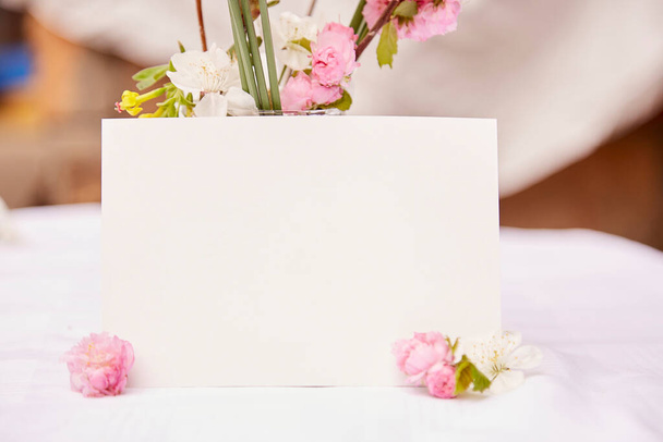 春のピンク、白、黄色の花の花瓶で繊細なはがきモックアップ。女性の日、招待状、母の日、結婚式、誕生日カードのコンセプト。自然回復の概念。審美的なコテージコア. - 写真・画像