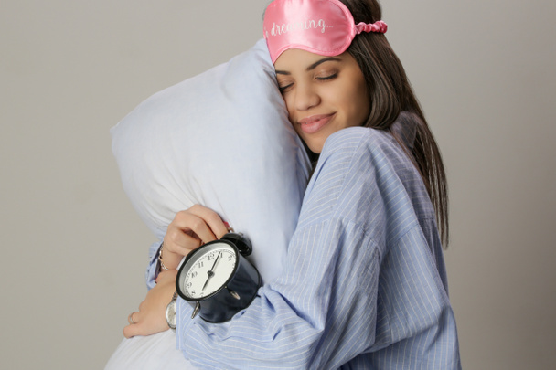 Studio portrait of gorgeous young woman with pillow and eye sleeping mask - 写真・画像